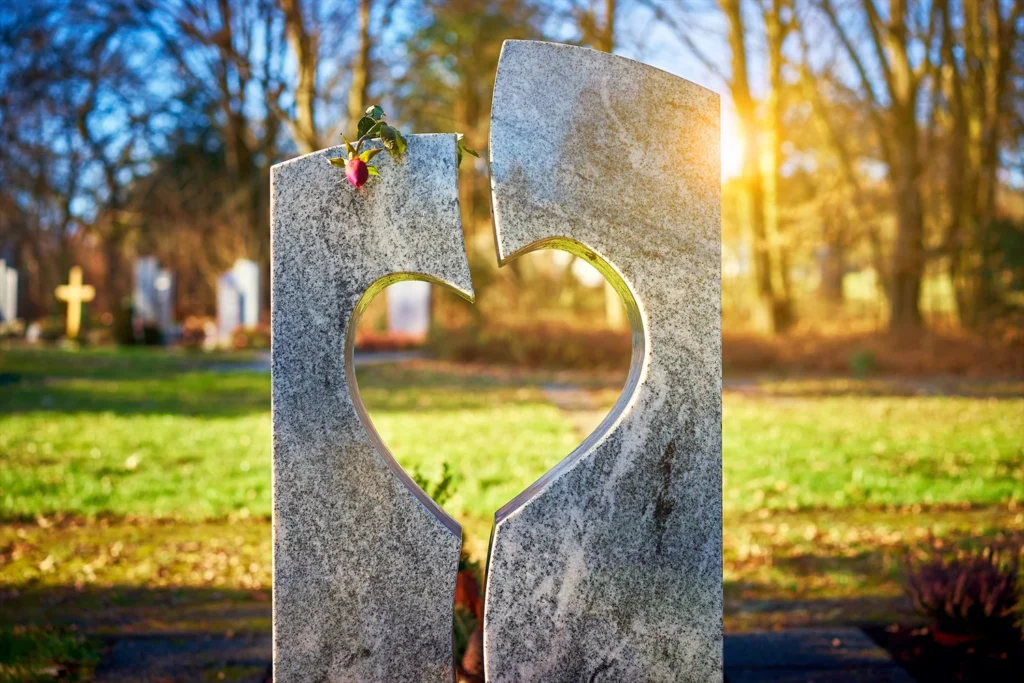 Uitvaart regelen Grafsteen met hartvormige uitsparing in zonlicht, symbool voor liefde, herinnering en respect – UitvaartNummer1.
